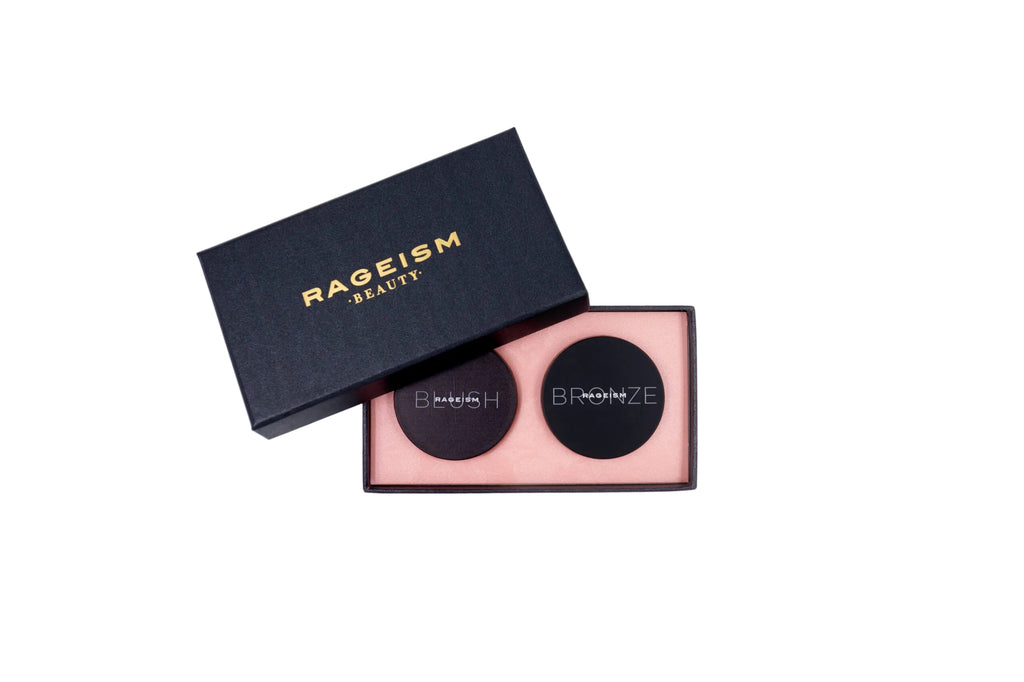 An open black RAGEISM BEAUTY box showing two round black makeup pans on a pale pink tray, photographed on a clean white background.