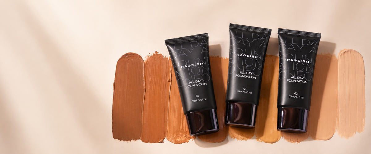Three black tubes of Makenzi All Day Foundation in shades 60, 50, and 40 are arranged on top of vertical swatches of warm beige and brown foundation cream on a light beige background.