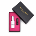 Rageism Beauty gift set featuring a white serum bottle with a silver pump and a black lip balm tube, presented in a black box with a bright pink interior, alongside the black outer lid with gold lettering.
